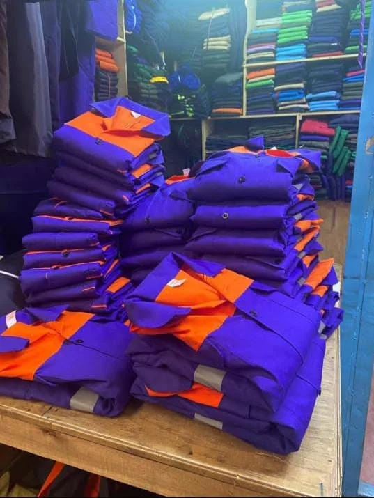 Stacked purple and orange branded workwear with reflective strips, folded ready for delivery