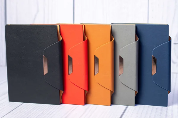 Gold strip executive notebooks with a metal clasp, in black, red, orange, grey and navy